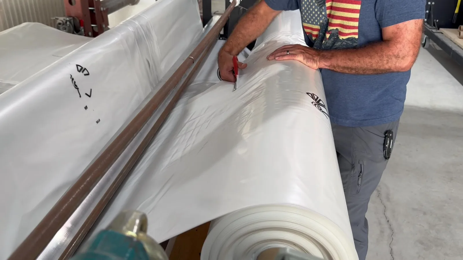 An operator cuts greenhouse film on the rewinding machine.