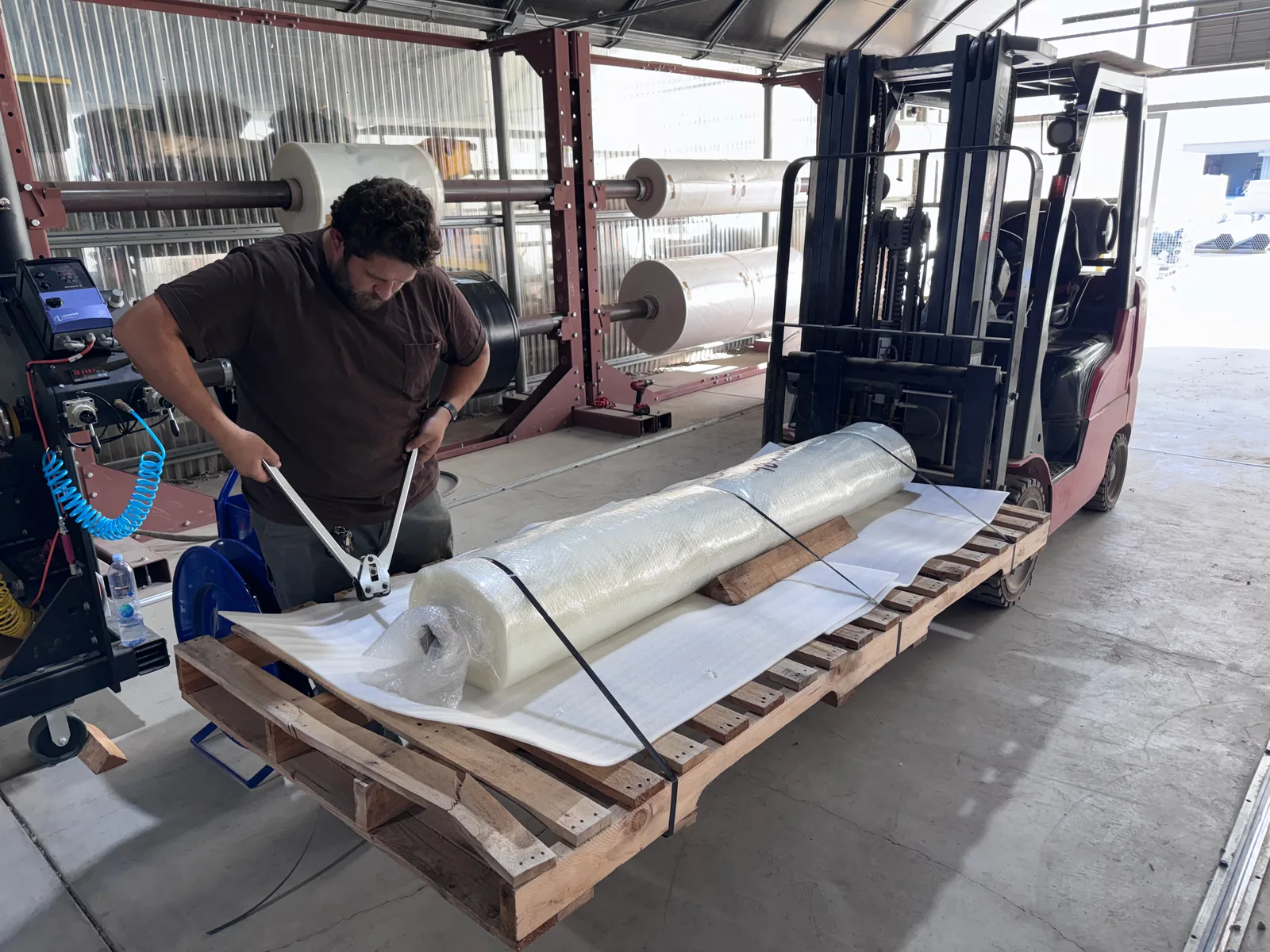 A GHP team member secures wrapped film rolls to a pallet.