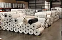 Rows of greenhouse plastic master rolls stored inside a warehouse