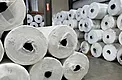 Close view of stacked greenhouse plastic master rolls inside a warehouse